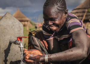 text to give video report showing Ugandan boy benefitting from donor funded clean water installation project