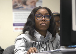 nonprofit fundraising video IT student at computer statio listening to off screen instructor