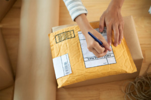 woman addressing small package for mailing from home office