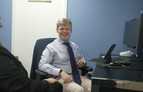 thumbnail for a customized employment video showing an employer meeting with an employee at his computer desk